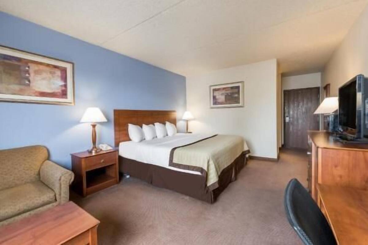 Une chambre d’hôtel comprenant un lit, des lampes de chevet, une télévision, un bureau et une chaise.