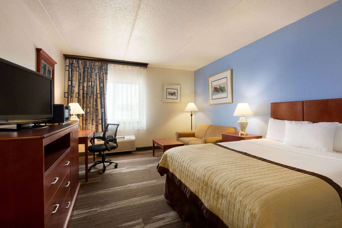 Une chambre d’hôtel avec un grand lit, un bureau avec une télévision, une chaise, un canapé et deux lampes.