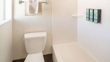 Een badkamer met toilet, bad en handdoekhouder.