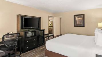 A hotel room with a bed, a desk with a television, a chair, a wardrobe, and a mirror.