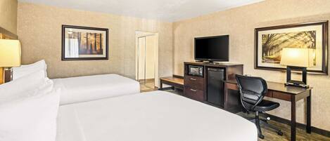 A hotel room with two beds, a desk with a TV, a chair, and a desk lamp.
