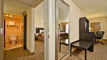 A hotel room with a bathroom, a bed, a desk, and a chair.