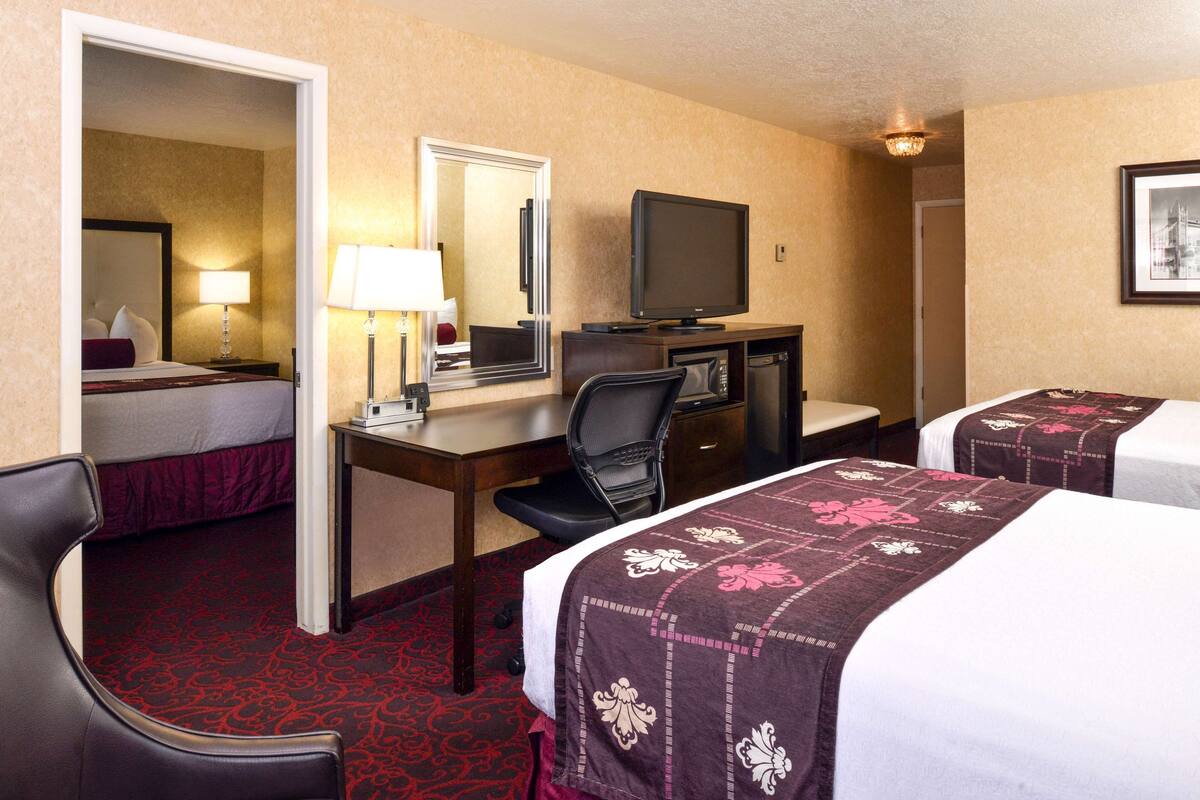 A hotel room with a bed, a desk, a chair, a television, and a mirror.