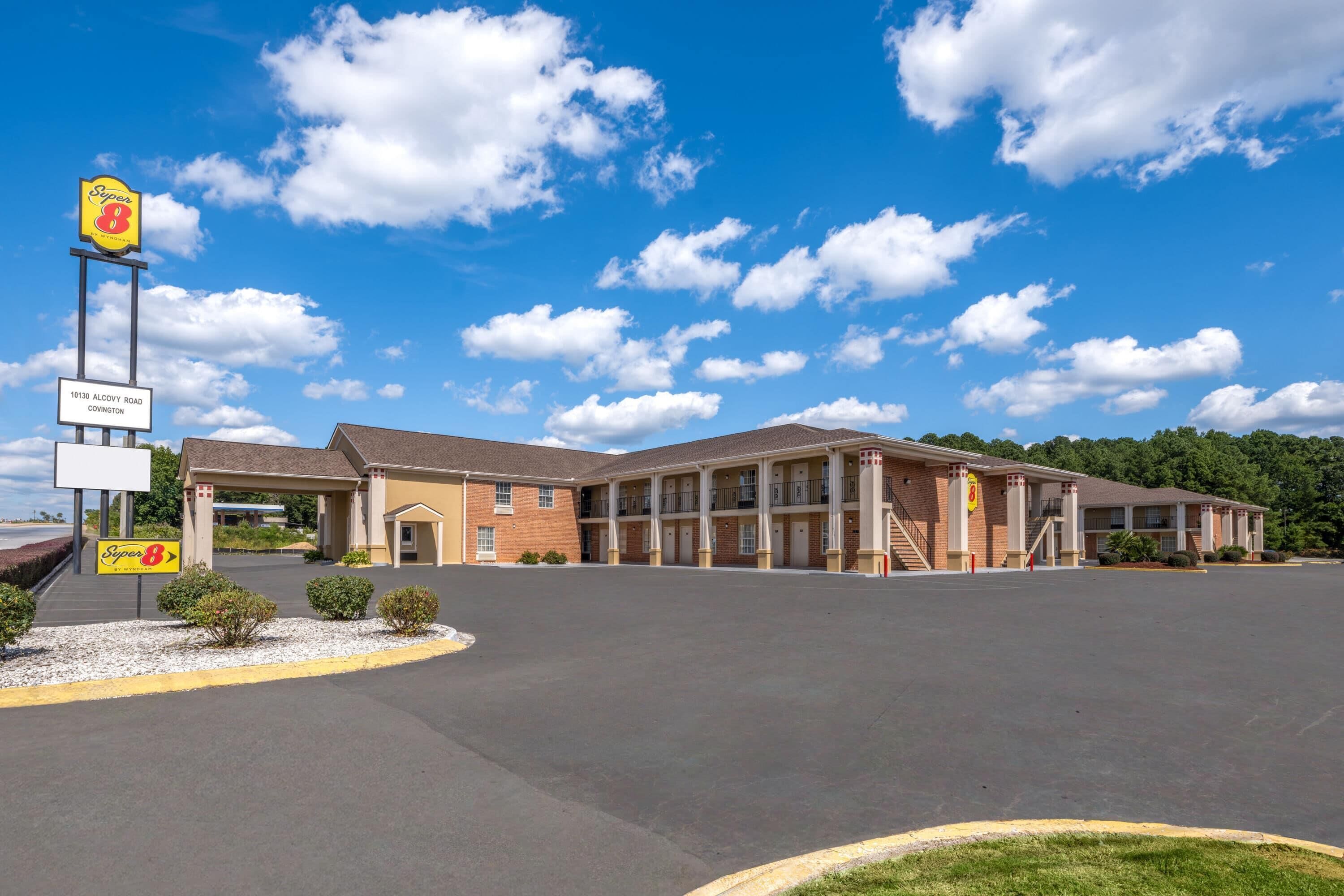 A Super 8 motel with a two-story building, a parking lot, and a clear blue sky.