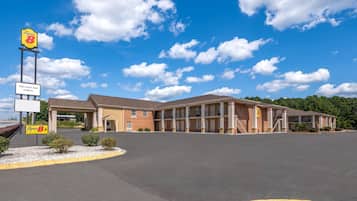 A Super 8 motel with a two-story building, a parking lot, and a clear blue sky.