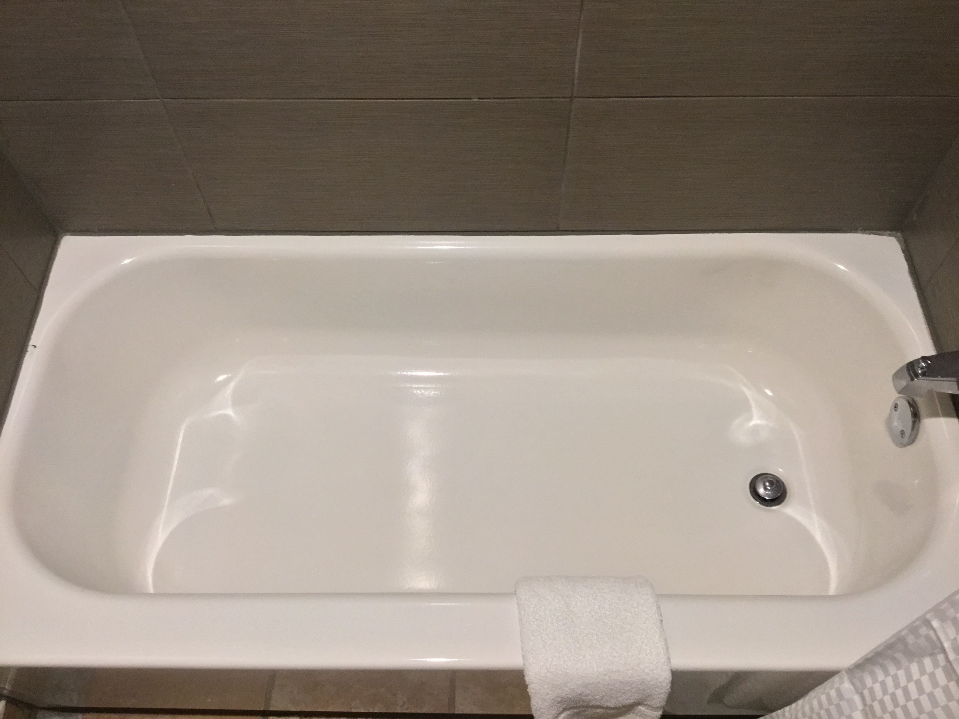 Ett vitt badkar med en kran och en handduk som hänger på kanten.