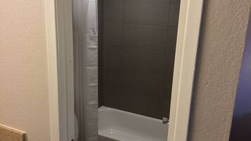 A bathroom with a shower, toilet, and bathtub.