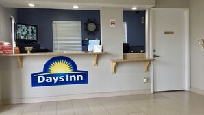 Zona de recepción de un hotel Days Inn, con un reloj, un televisor y un letrero que indica 'No se admiten mascotas'.