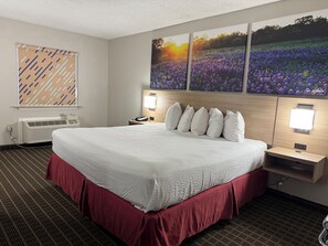 A hotel room with a large bed, a wall-mounted TV, a bedside table with a lamp, and a window with blinds. - Days Inn by Wyndham San Antonio Morgan's Wonderland / IH-35 N (San Antonio)