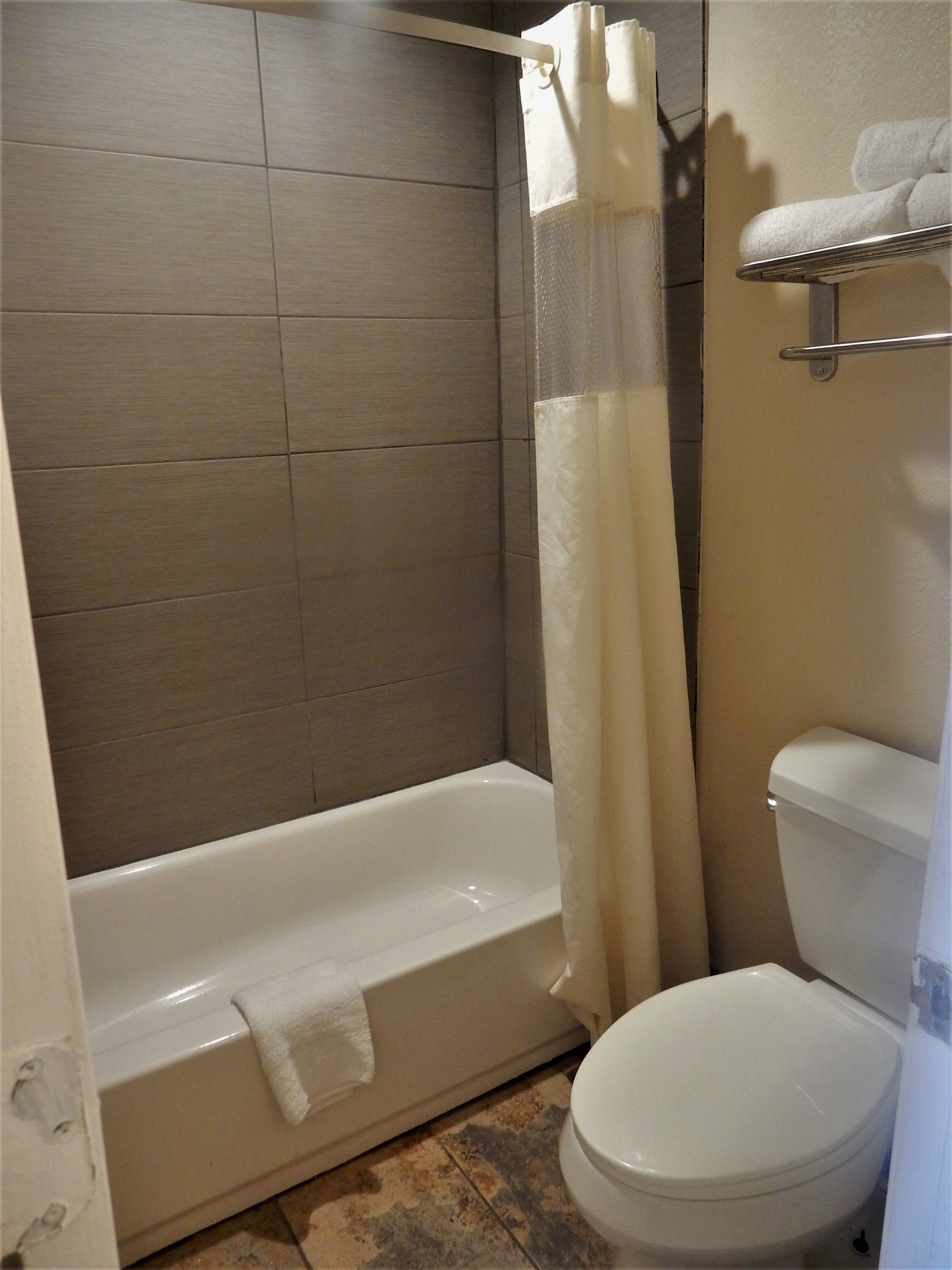 A bathroom with a bathtub, toilet, and shower curtain.