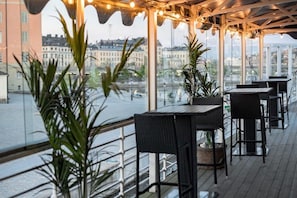 An outdoor terrace with tables and chairs, potted plants, and a view of the cityscape. - Mälardrottningen Hotel (Stockholm)