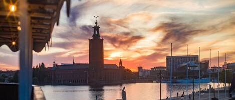 A waterfront view with a prominent tower, a modern building, and a promenade with people.