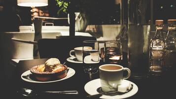 Una mesa de comedor con un postre, tazas y una vela.
