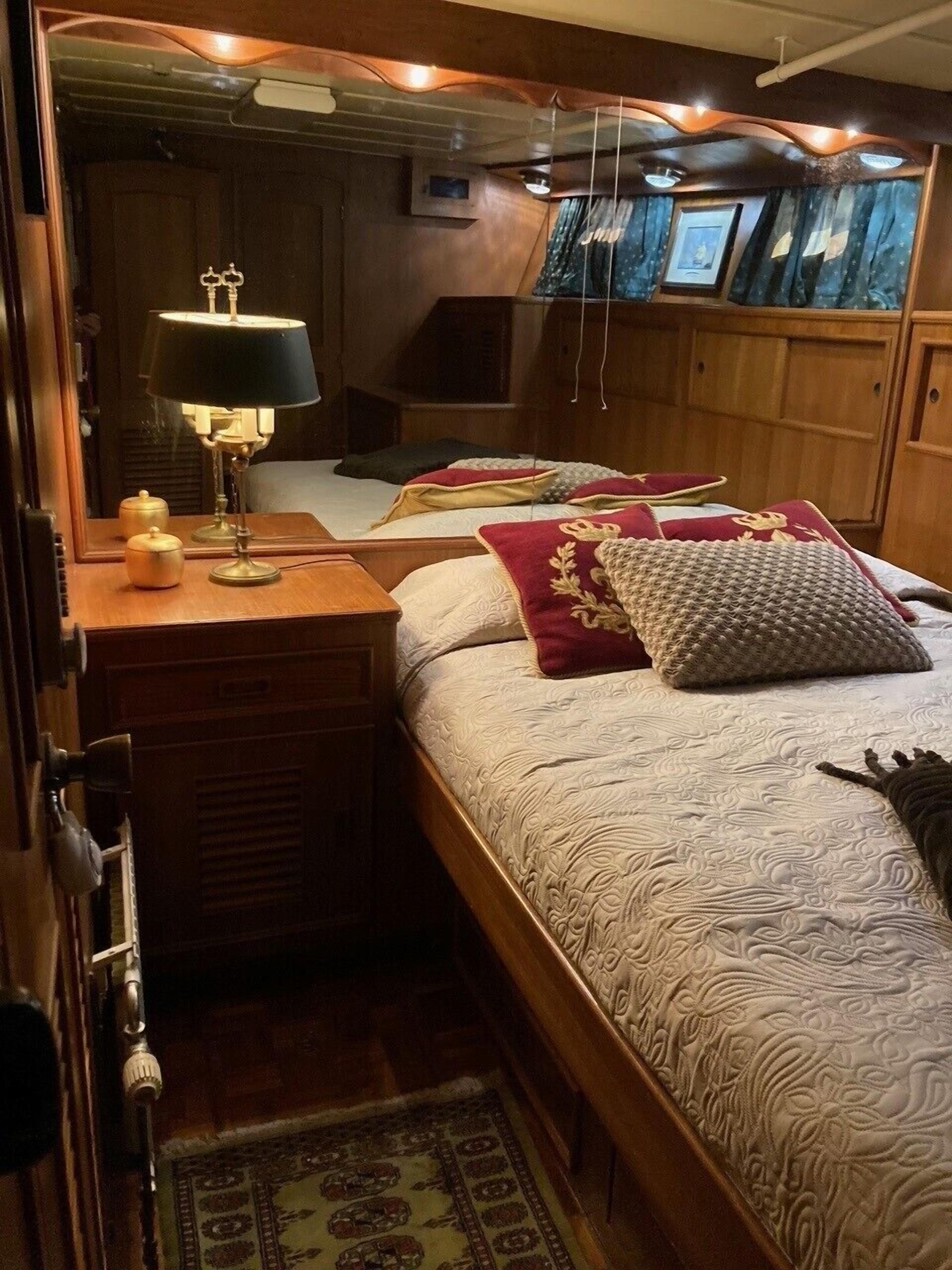 A cozy bedroom with a wooden bed, a bedside lamp, and a mirror.