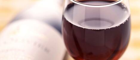 A wine glass filled with red wine next to an open wine bottle.