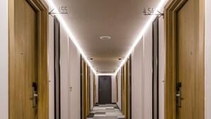 Un pasillo de hotel con puertas de madera, alfombra a cuadros e iluminación en el techo.