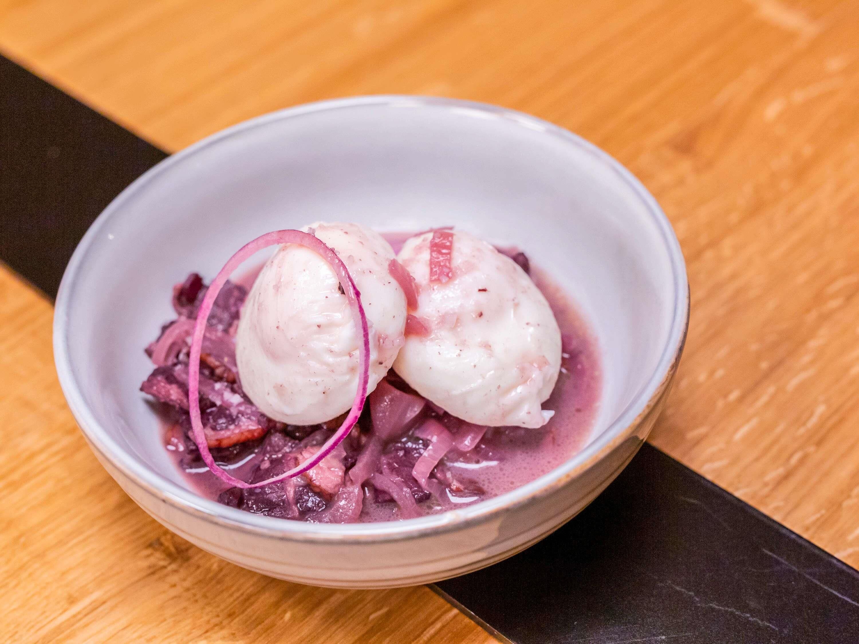 A bowl of dessert with two scoops of ice cream and a purple sauce.