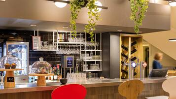 A bar area with a counter, shelves of glasses, and hanging plants.