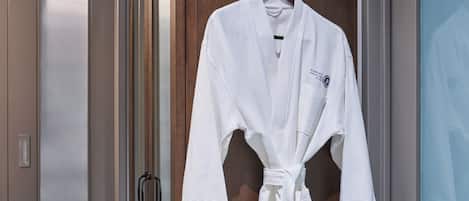 A white robe hanging on a wooden door in a hotel room.