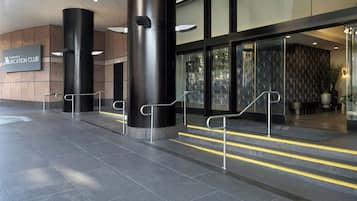 Een moderne hotelentree met een bord voor de Marriott Vacation Club, een trap die naar de lobby leidt, en een bekeken muur.
