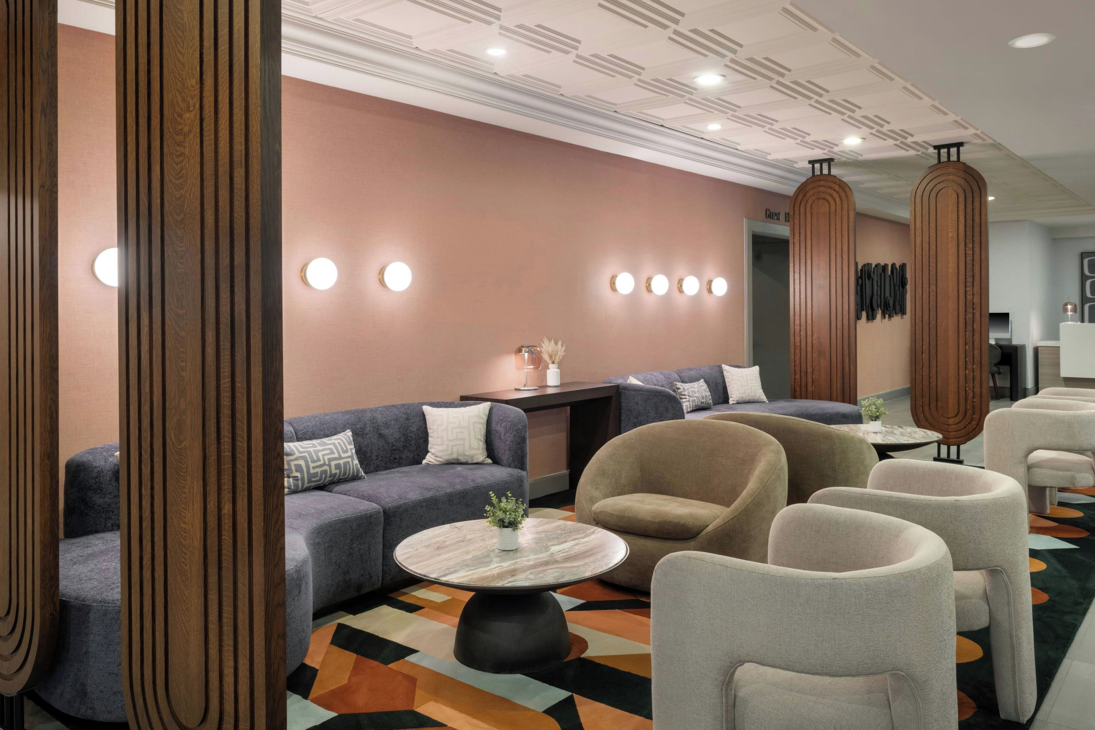 A hotel lobby with sofas, armchairs, a coffee table, and a reception desk.