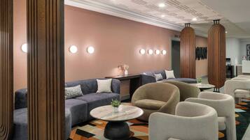 A hotel lobby with sofas, armchairs, a coffee table, and a reception desk.