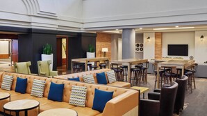 A spacious lobby with a high ceiling, leather seating, multiple tables, and a large flat-screen TV mounted on the wall. - Marriott Vacation Club®, San Diego (San Diego)
