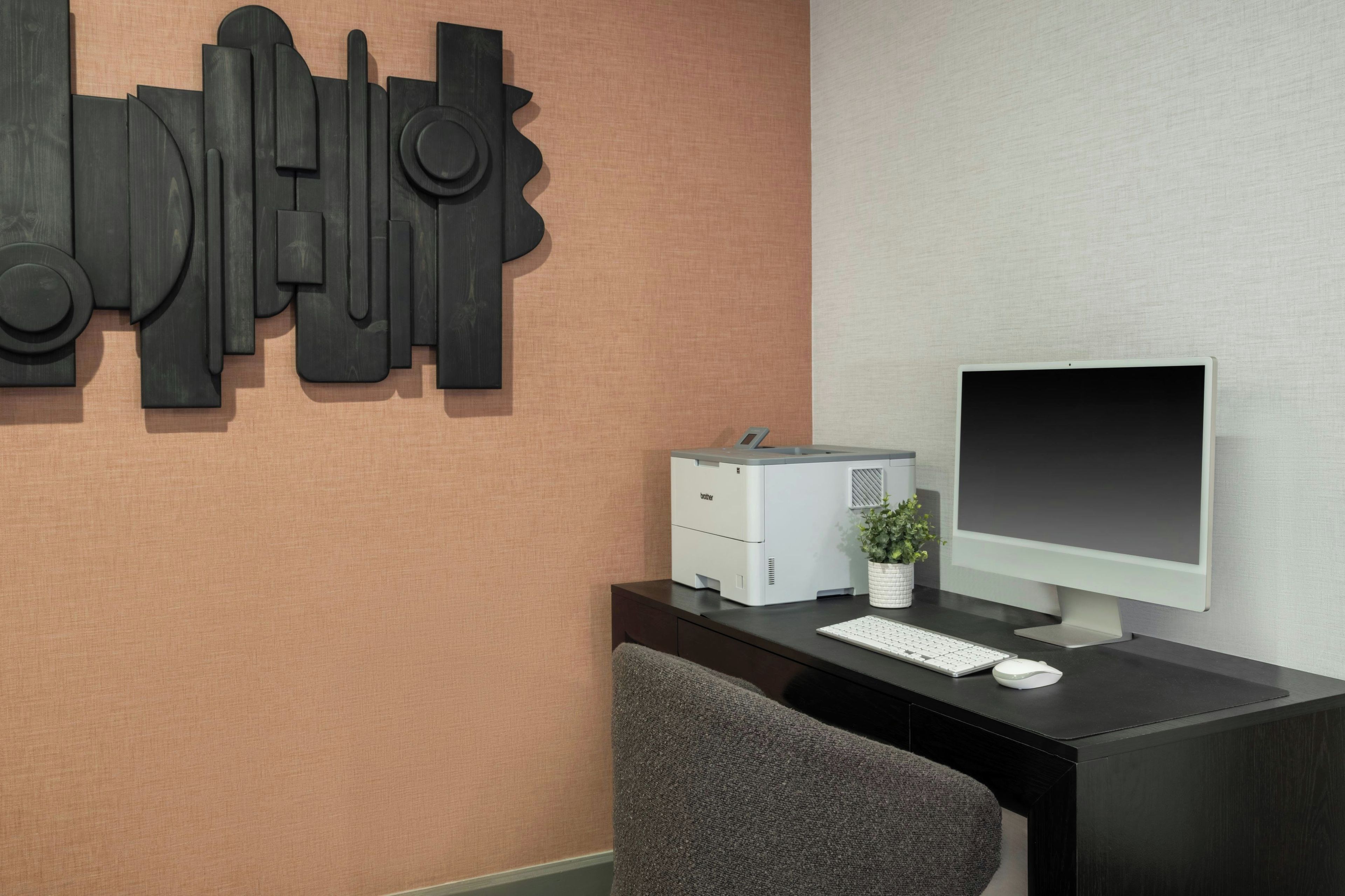 Un bureau moderne, équipé d’un ordinateur de bureau, d’un clavier, d’une souris et d’une petite plante en pot.