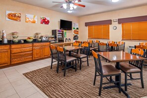 A dining area with wooden cabinets, a coffee station, and multiple tables and chairs.
