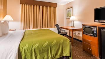 A hotel room with a bed, a desk, a television, a microwave, and a chair.