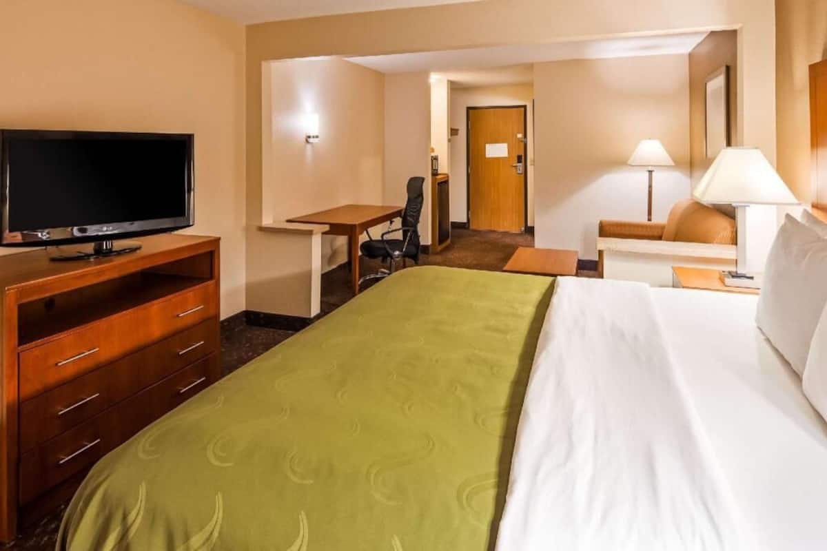 A hotel room with a bed, a desk, a television, and a chair.