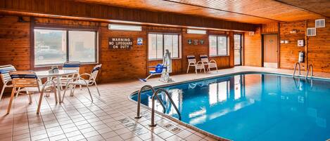 An indoor swimming pool with tiled flooring, wooden walls, and a lifeguard station.
