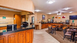 A hotel lobby with a reception desk, a coffee station, and a dining area with tables and chairs. - Quality Inn Tomah (Tomah)