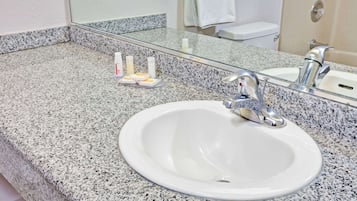 A bathroom with a granite countertop, a white sink, and a mirror.