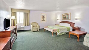 A hotel room with a bed, a desk, a chair, a TV, and two paintings on the walls. - Days Inn & Suites by Wyndham Fullerton (Fullerton)