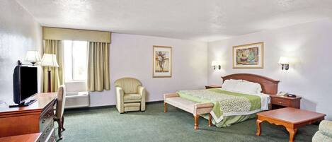 A hotel room with a bed, a desk, a chair, a TV, and two paintings on the walls.
