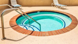 A swimming pool with a tiled edge, a ladder, and two lounge chairs. - Days Inn & Suites by Wyndham Fullerton (Fullerton)