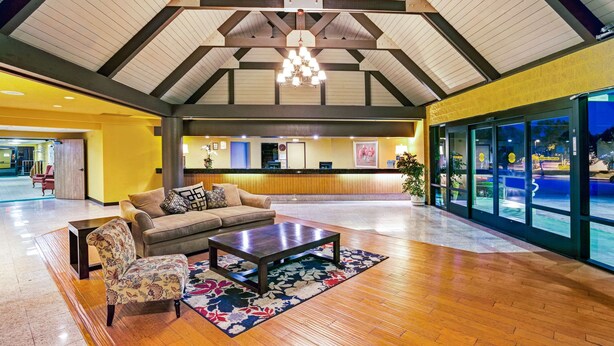 A spacious lobby with a wooden floor, a sofa, a coffee table, and a chandelier. - Days Inn & Suites by Wyndham Fullerton (Fullerton)