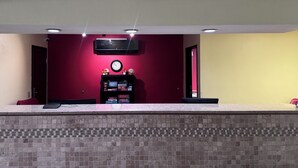 A reception area with a tiled counter, a clock, and a black shelf with items.