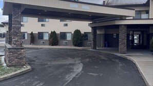 A two-story building with a covered entrance, stone pillars, and a parking lot.