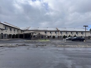 A multi-story hotel with a covered parking area and a small garden.