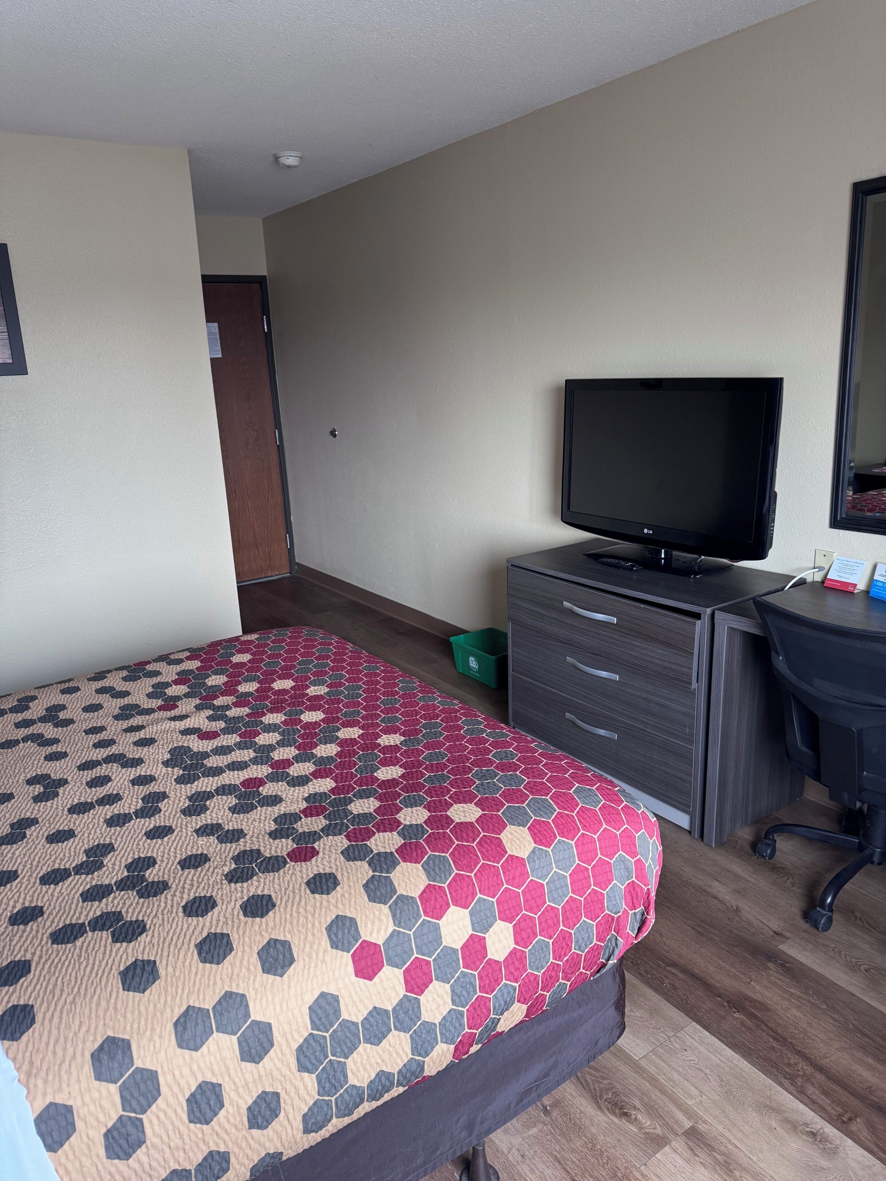 A hotel room with a bed, a TV, a desk, and a chair.
