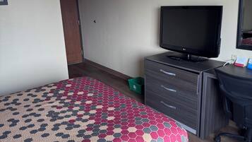 Ett hotellrum med en säng, en tv, ett skrivbord och en stol.