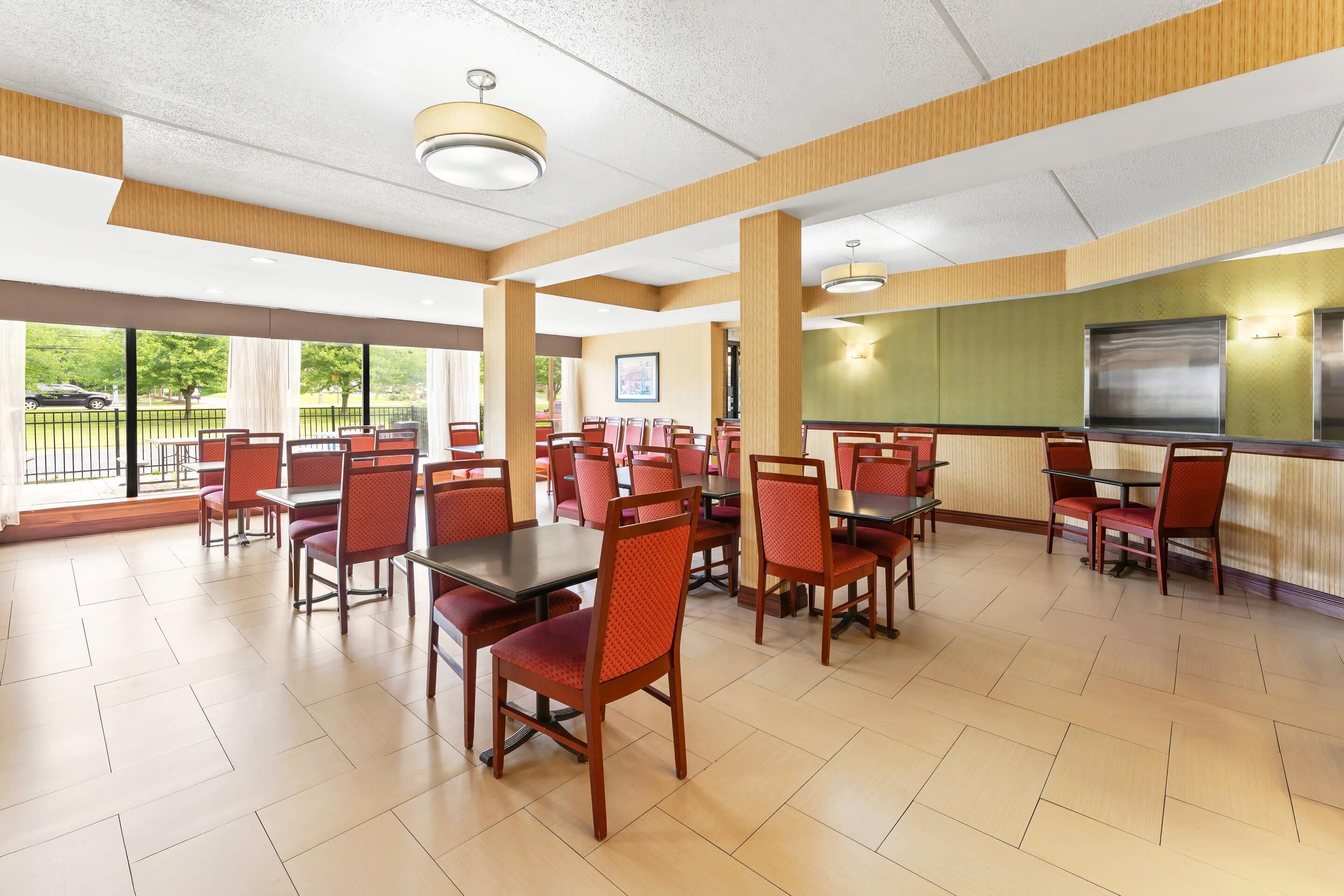 Une salle à manger spacieuse avec de hauts plafonds, de grandes fenêtres et une vue sur l’extérieur.