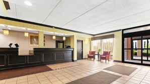 A hotel reception area with a reception desk, two chairs, and a large window. - Comfort Inn Lehigh Valley West - Allentown (Allentown)