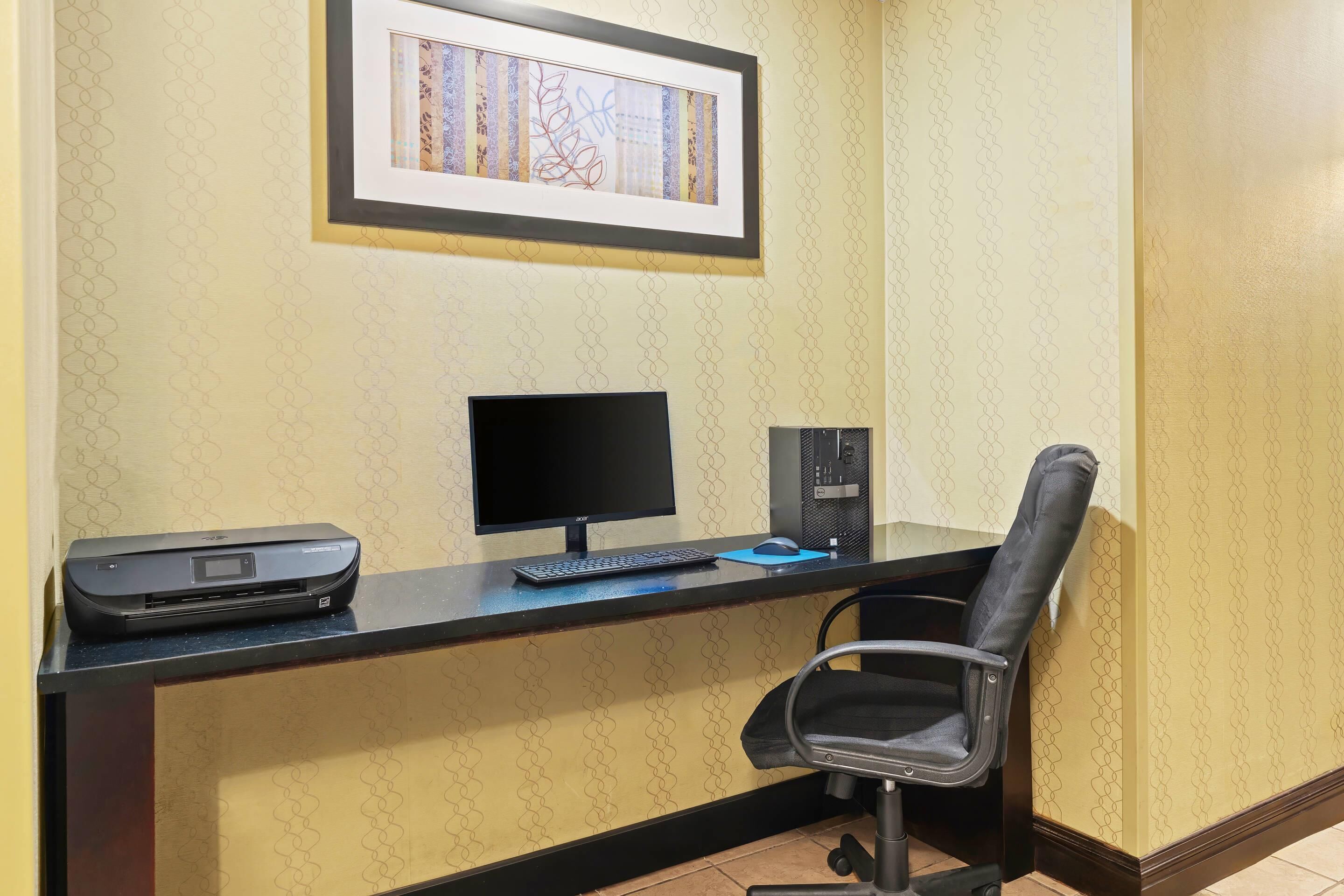 A reception desk with a computer, printer, and chair.