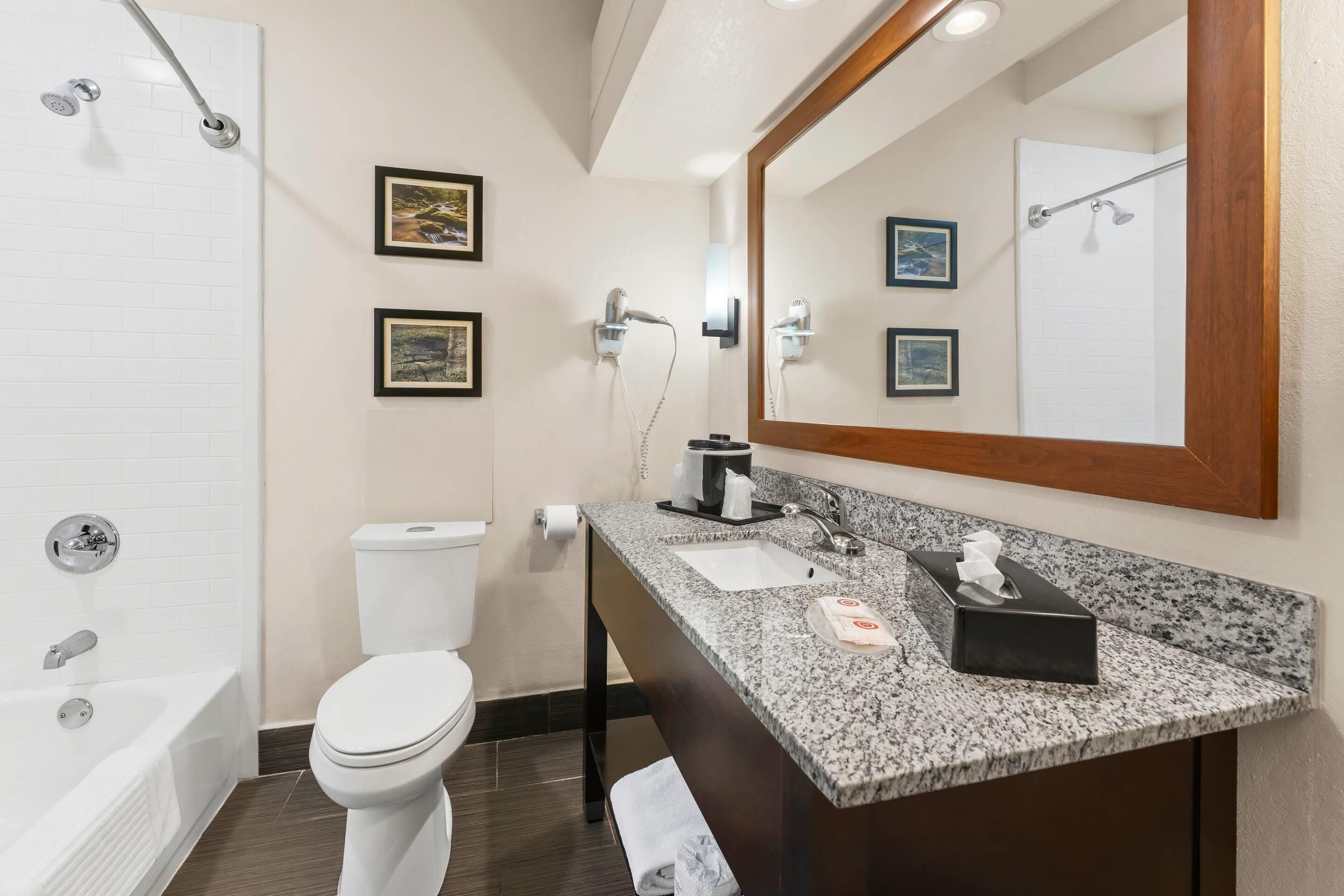 Un bagno moderno con vasca, servizi igienici, lavandino e uno specchio grande.