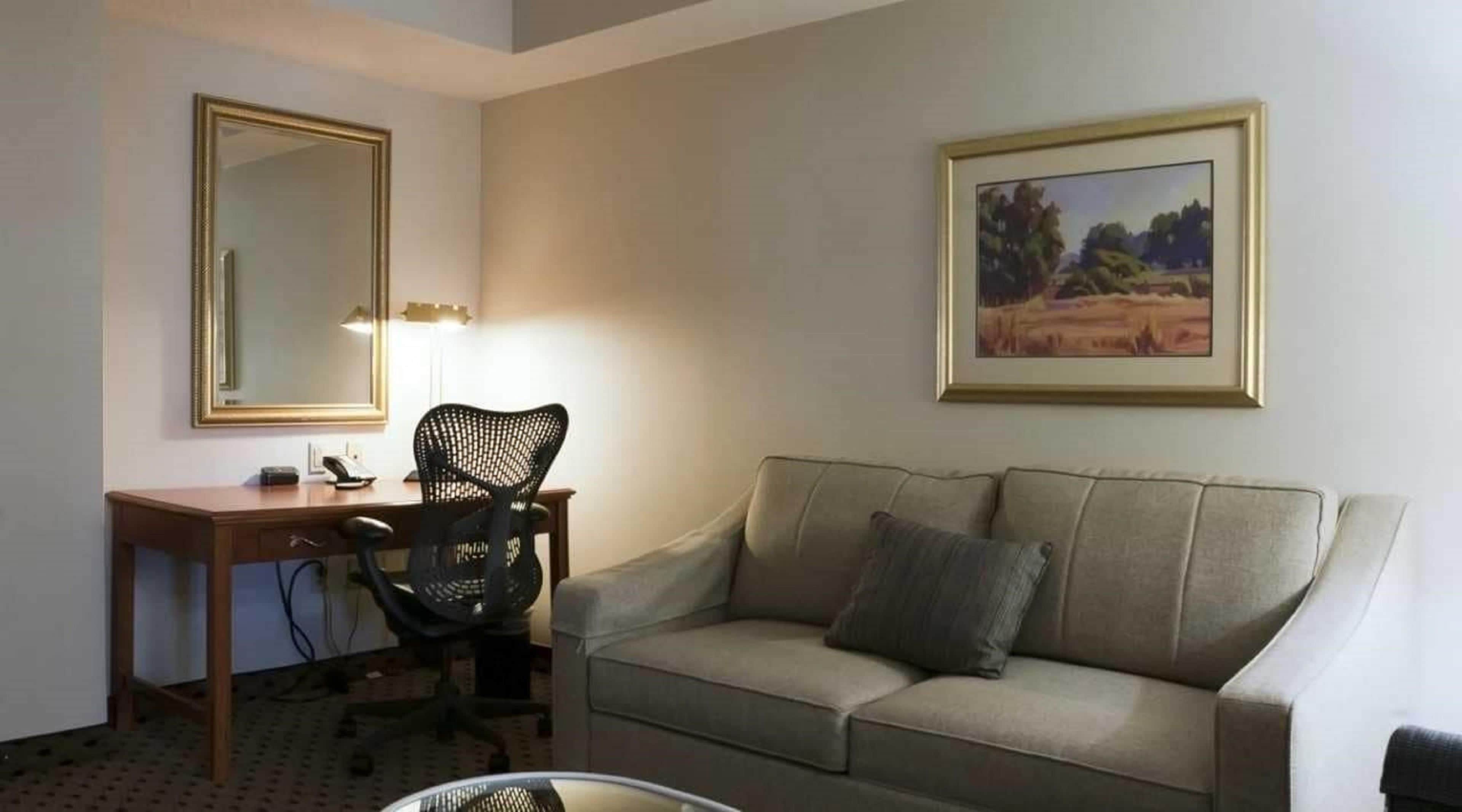 Um quarto com escrivaninha, cadeira e sofá.