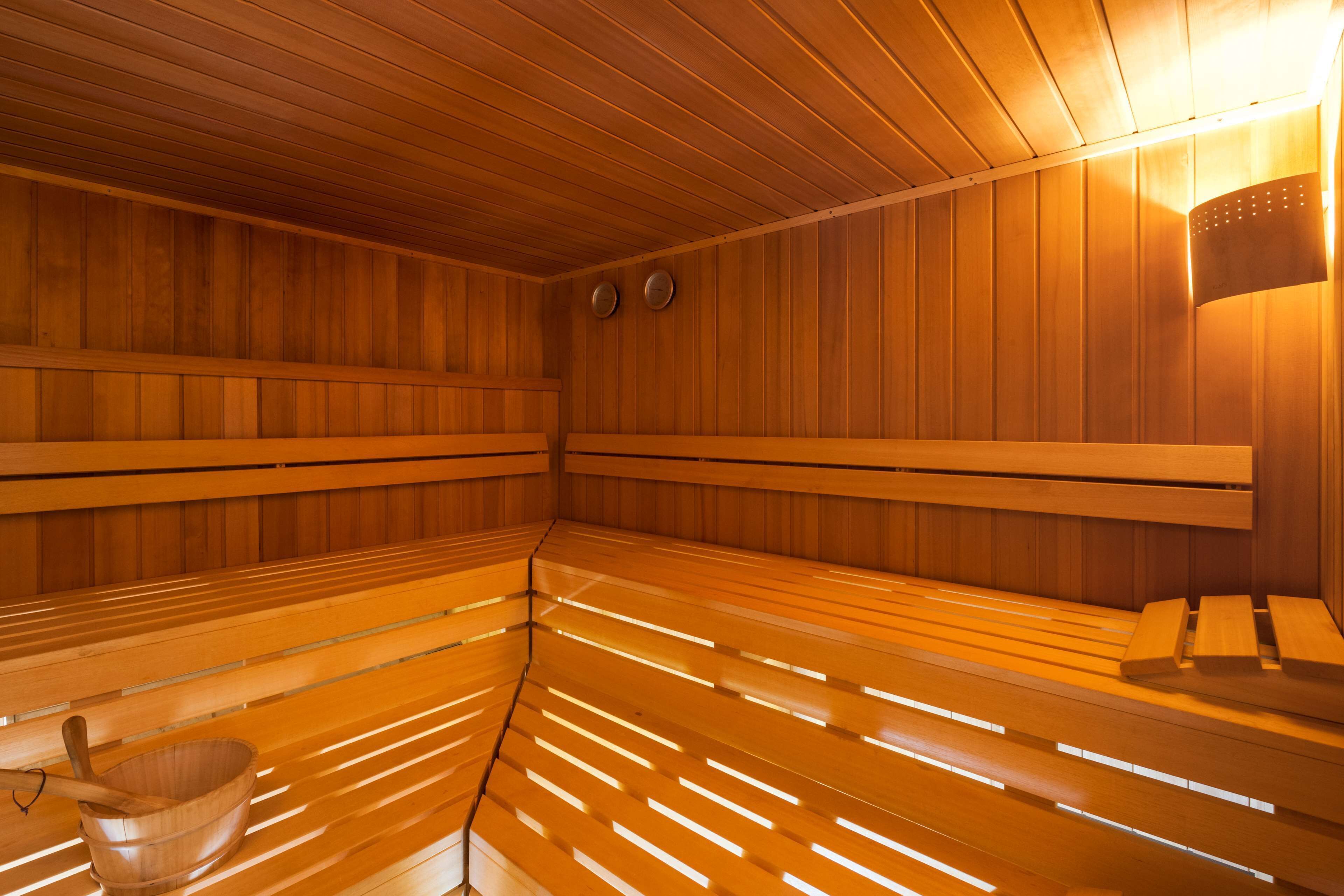 Una sauna con bancos de madera y un balde de madera.