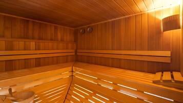 Una sauna con bancos de madera y un balde de madera.